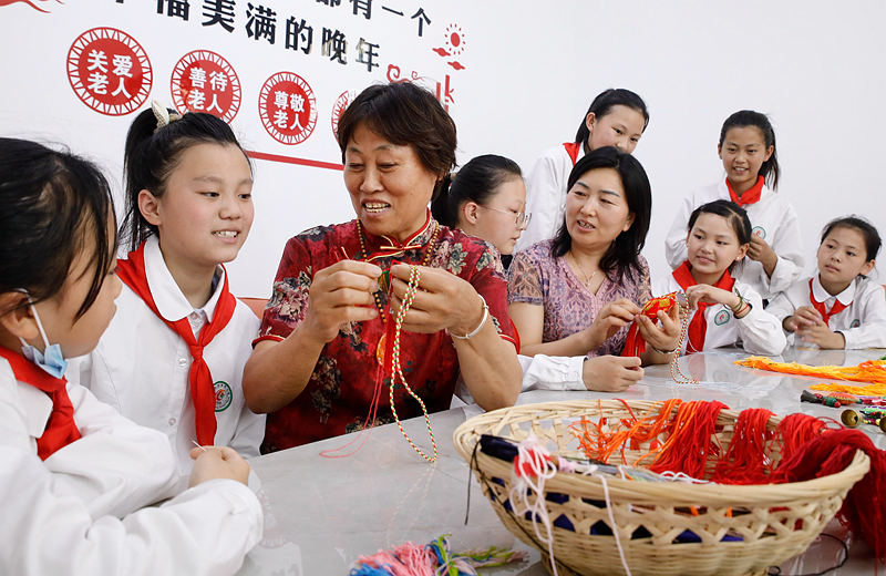 6月2日，河南省開封市尉氏縣實驗小學師生和獨居老人一起包粽子、縫香包，感受傳統節日文化魅力。李新義攝 