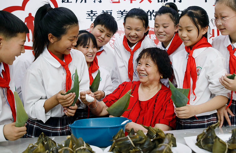 6月2日，河南省開封市尉氏縣實驗小學師生和獨居老人一起包粽子、縫香包，感受傳統節日文化魅力。李新義攝 