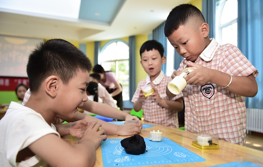 小朋友们学习制作手工月饼。黄政伟摄