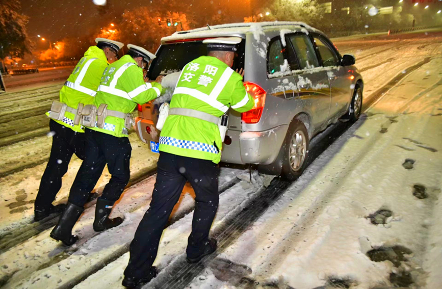 河南洛阳交警在雪中帮助抛锚车辆。王永超摄