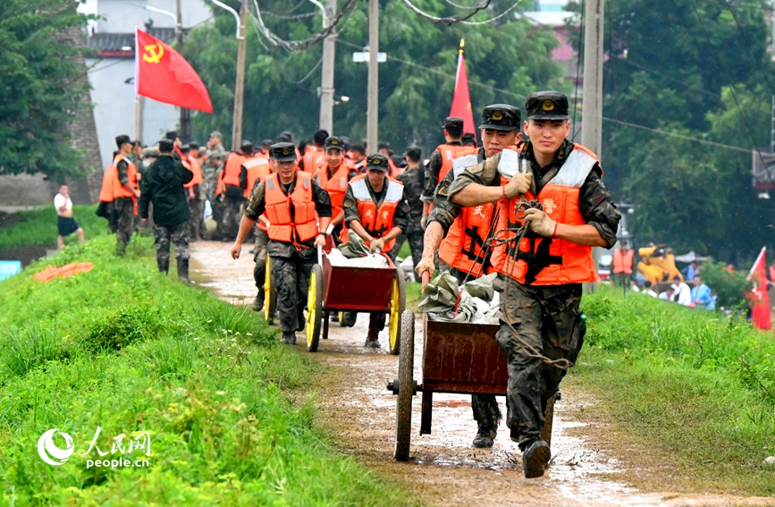 7月16日，在河南省社旗县赊店镇的潘河大堤上，武警官兵正在抢运防汛沙袋。人民网 辛静摄