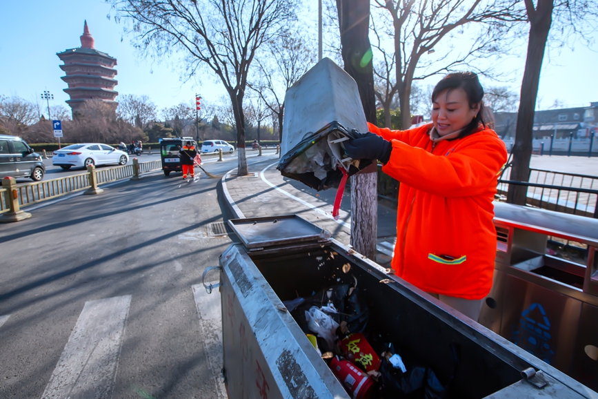 1月29日，安阳市环卫工刘仙芬清倒路边垃圾箱里的垃圾。毕兴世摄