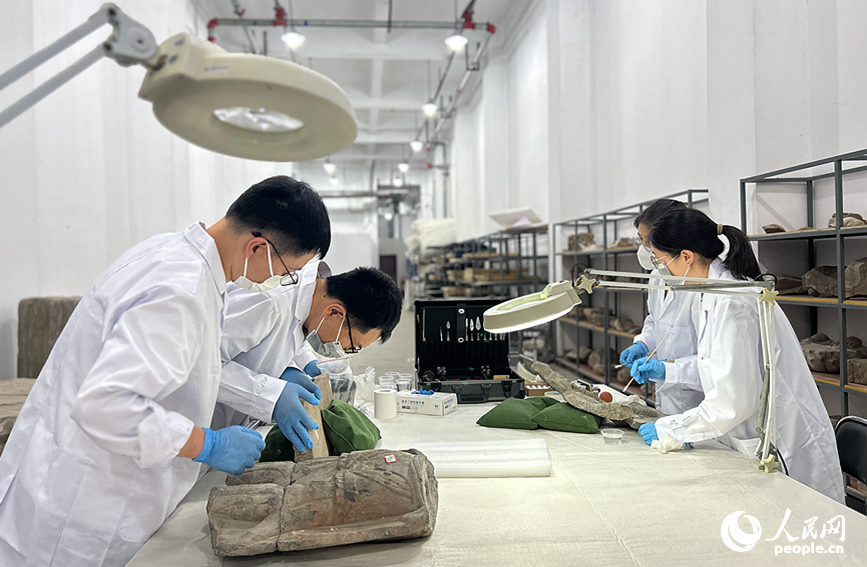 龙门石窟研究院的工作人员在修复石窟文物。 人民网 霍亚平摄