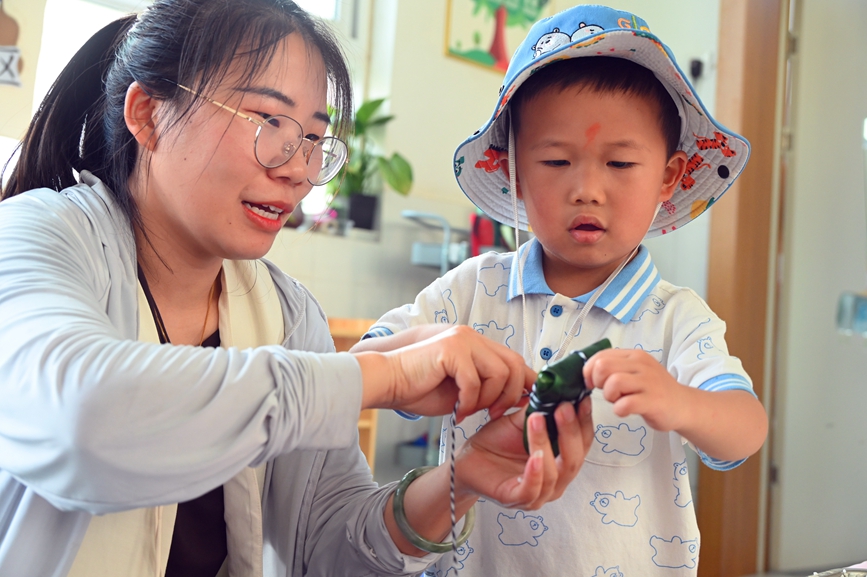 5月28日，河南省南陽市社旗縣第三幼兒園舉辦“雙節同慶 童心‘粽’在”親自游園活動，家長和孩子一起包粽子。申鴻皓攝