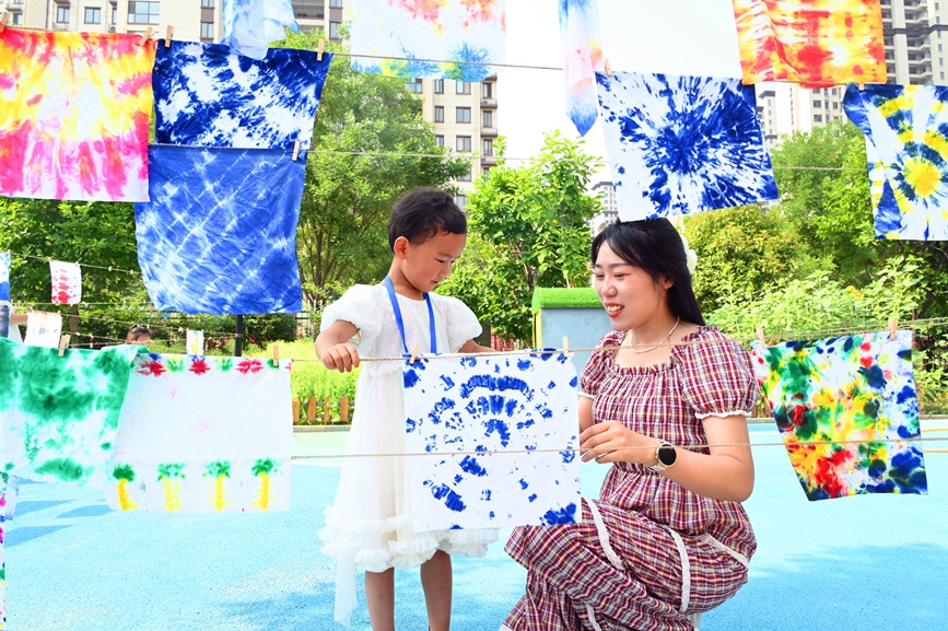 5月28日，河南省南陽市社旗縣第三幼兒園舉辦“雙節同慶 童心‘粽’在”親自游園活動，家長和孩子一起晾晒扎染作品。申鴻皓攝