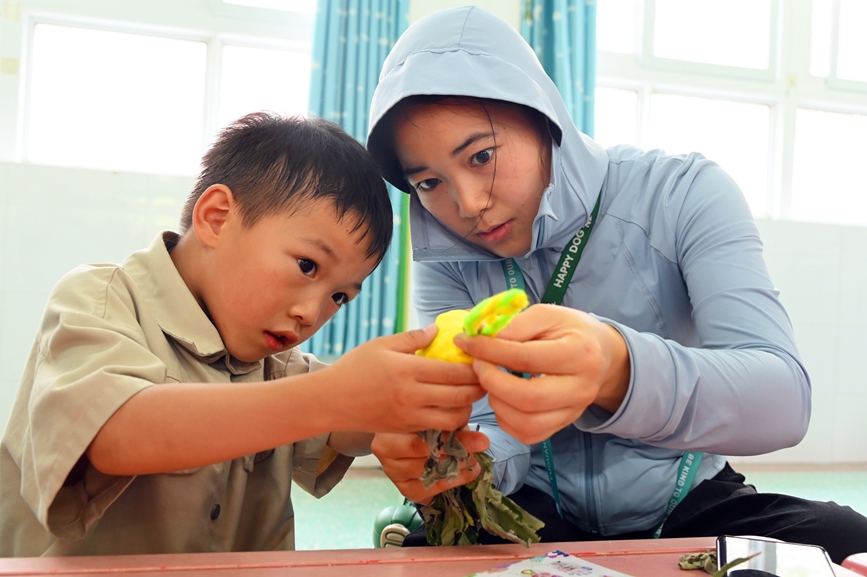 5月28日，河南省南陽市社旗縣第三幼兒園舉辦“雙節同慶 童心‘粽’在”親自游園活動，家長和孩子在制作艾草挂件。申鴻皓攝