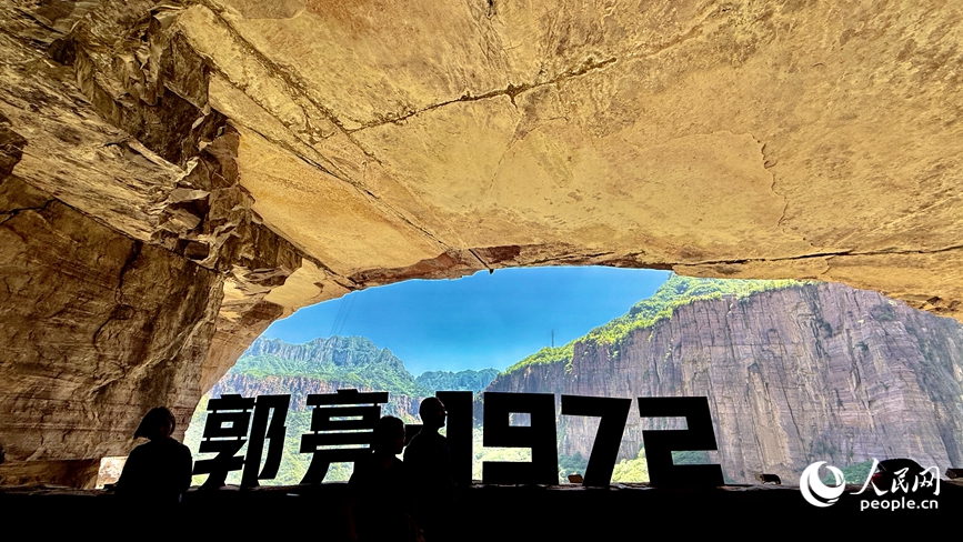 灯光漫过凿痕，游人的影子贴在岩壁上，与五十年前的凿山印记重叠。人民网记者 王佩摄