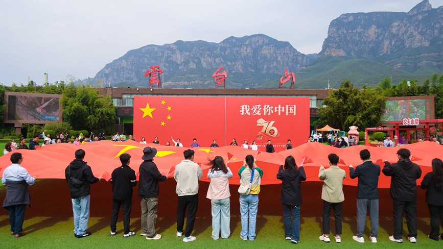 10月1日，云台山百家岩广场，现场游客传递巨幅五星红旗，共同《歌唱祖国》。 孙清新摄