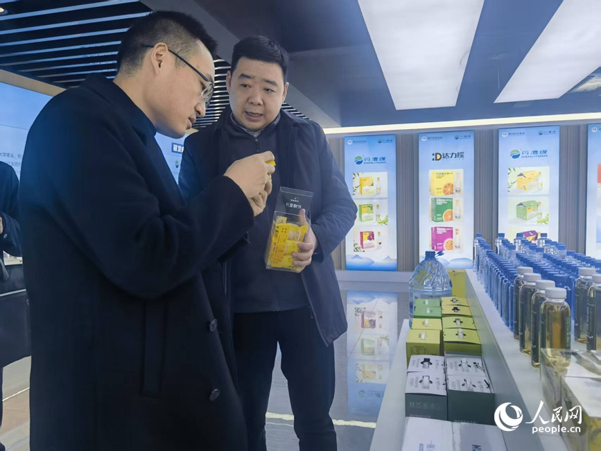 李哲(左)向人民网记者介绍公司产品。人民网记者 尚明桢摄