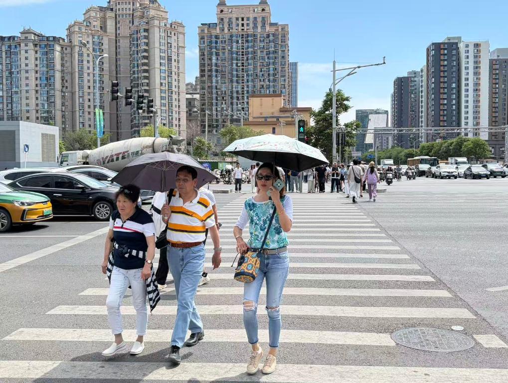 5月10日，市民在北京市朝阳区街头打伞防晒。新华社记者 陈钟昊 摄