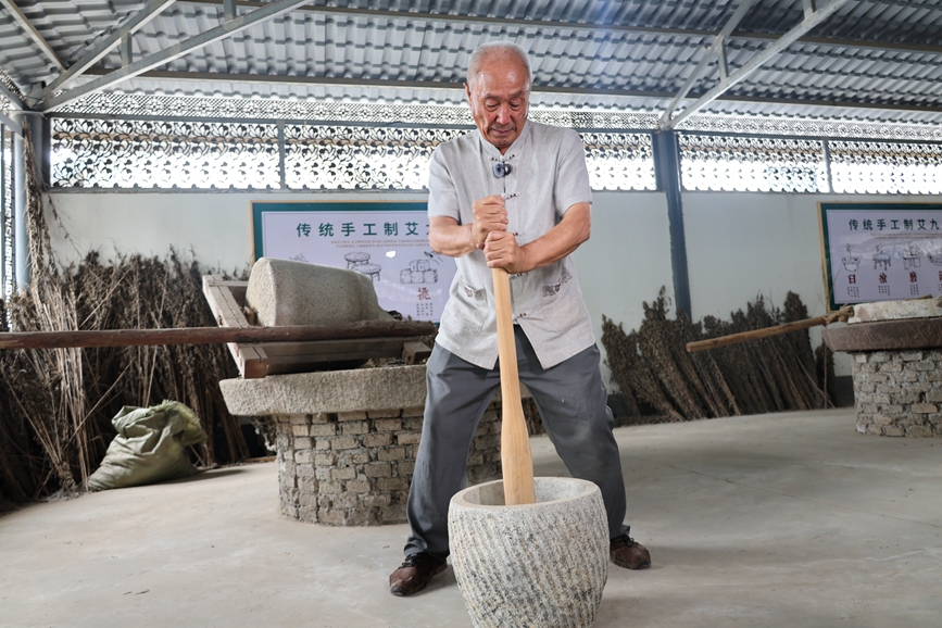 非物质文化遗产代表性传承人正在运用“古法九技”之一的石臼人工捣艾、制艾。张新军摄