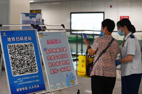 9月15日，郑州地铁5号线工作人员帮助乘客扫码。